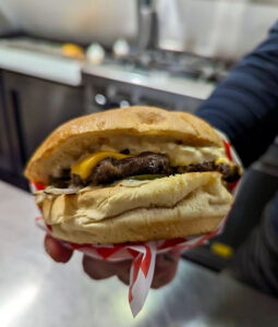 The Shed Eatery: Close up of hand holding beef burger